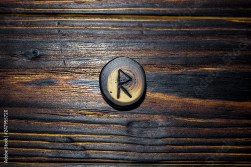 Rune Raido carved from wood on a wooden background - Elder Futhark