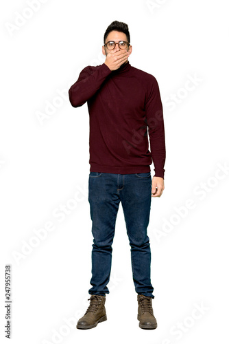 Full-length shot of Handsome man with glasses covering mouth with hands for saying something inappropriate on isolated white background