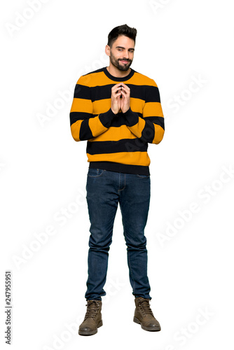 Full-length shot of Handsome man with striped sweater scheming something on isolated white background