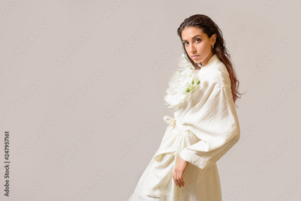 Portrait of Sensual Woman in white dress holding a white orchid against white background. Copy Space Portrait of Sensual Woman in white dress holding a white orchid against white background. Copy Space