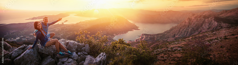 Happy Couple Watching the Sunset in the Mountains - obrazy, fototapety, plakaty 