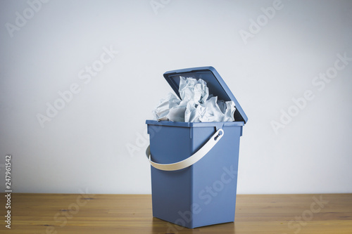 Gray trash can filled with crumpled paper