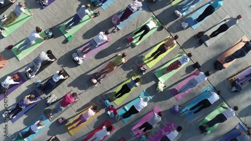 aerial view on big group of adults attending a yoga class outside in park