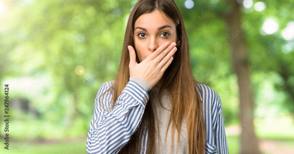 Young girl with striped shirt covering mouth with hands for saying something inappropriate at outdoors