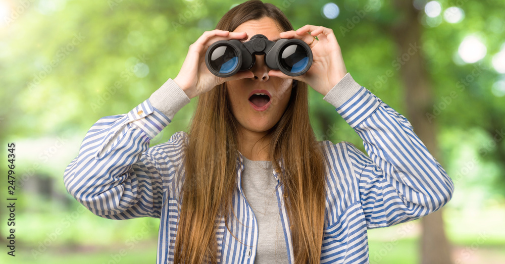 Young girl with striped shirt and looking in the distance with binoculars at outdoors Young girl with striped shirt and looking in the distance with binoculars at outdoors