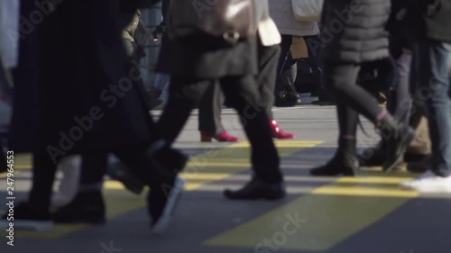 Slow motion shot of many people carrying shopping bags while crossing a busy main street in Zürich city center on a cold and sunny winters day.