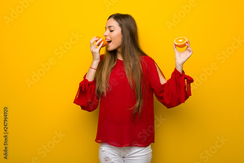 Young girl on vibrant yellow background with oranges