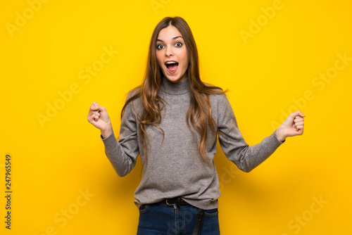 Young woman over yellow wall with surprise and shocked facial expression