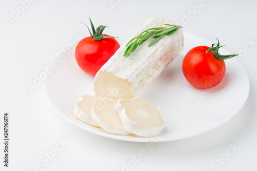Tasty goat cheese with rosemary and tomato, on white table
