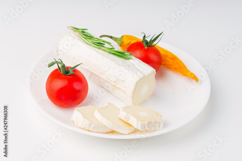 Tasty bushe cheese with rosemary and tomato, on white table
