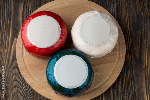 Colorful cheese packs on wooded table.
