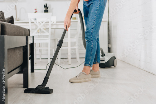 Cropped view of woman cleaning floor with vacuum cleaner