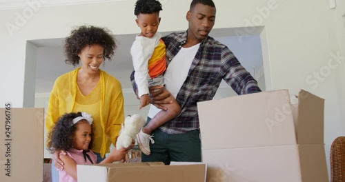 Front view of black family unpacking cardboard boxes at comfortable home 4k photo