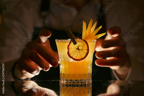 Fresh alcohol Penicillin cocktail with orange slice and ice cubes. Barmen making alcohol cocktail	 photo