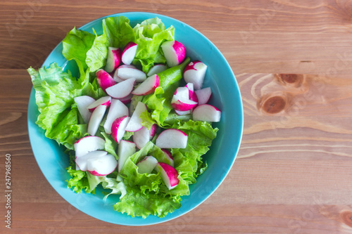 Bright salad. Radish and greens in blue plate