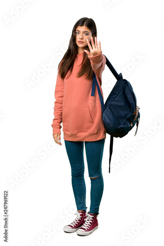 A full-length shot of a Teenager girl with sweatshirt and backpack making stop gesture denying a situation that thinks wrong