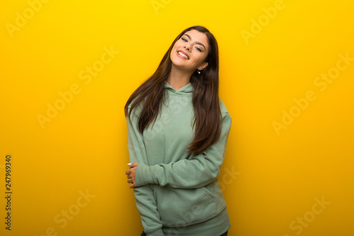 Teenager girl with green sweatshirt on yellow background With happy expression © luismolinero