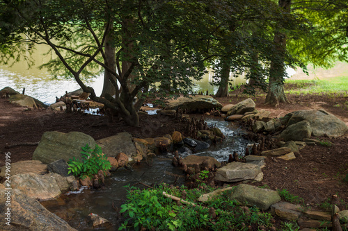 Beautiful park with a small river with stones. A stream with stones on the shore is rapidly running in the forest. Landscaping. Park Milliken Arboretum  Spartanburg  South Carolina  USA