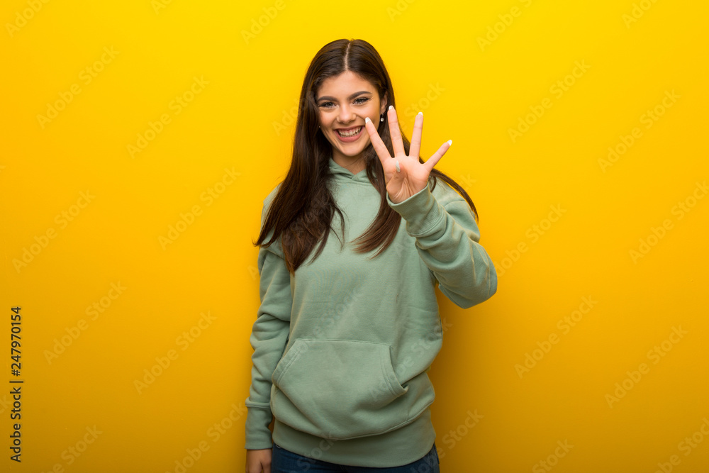Teenager girl with green sweatshirt on yellow background happy and counting four with fingers Teenager girl with green sweatshirt on yellow background happy and counting four with fingers