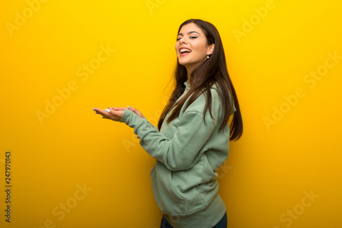 Teenager girl with green sweatshirt on yellow background applauding after presentation in a conference © luismolinero