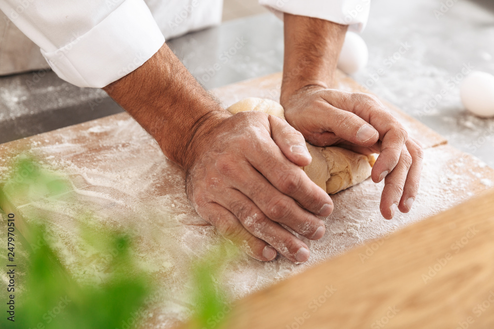 Closeup portrait of man chief making dough for bread, on table at bakery or kitchen Closeup portrait of man chief making dough for bread, on table at bakery or kitchen