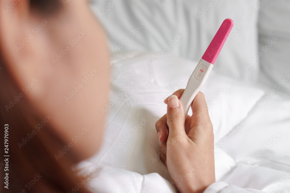 Unhappy young asian woman holding pregnancy test showing a negative result, Selective focus, Wellness and healthy concept, Infertility problem.