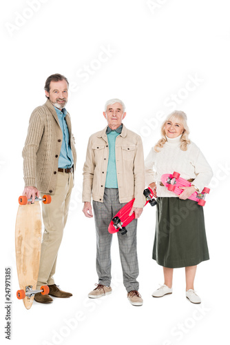 cheerful pensioners holding skateboards and smiling isolated on white