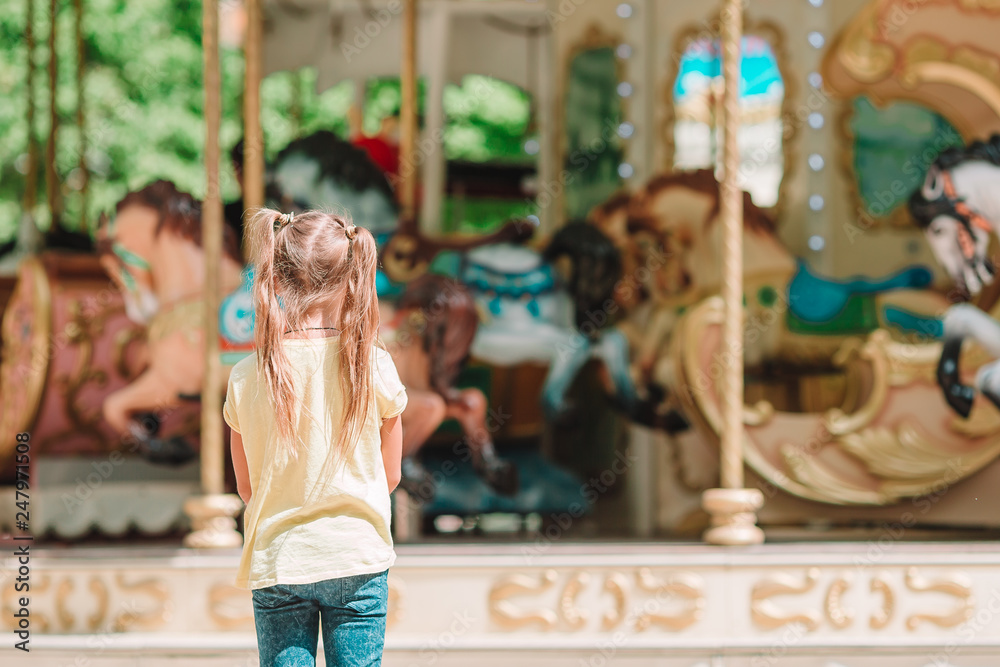 Adorable little girl near the carousel outdoors