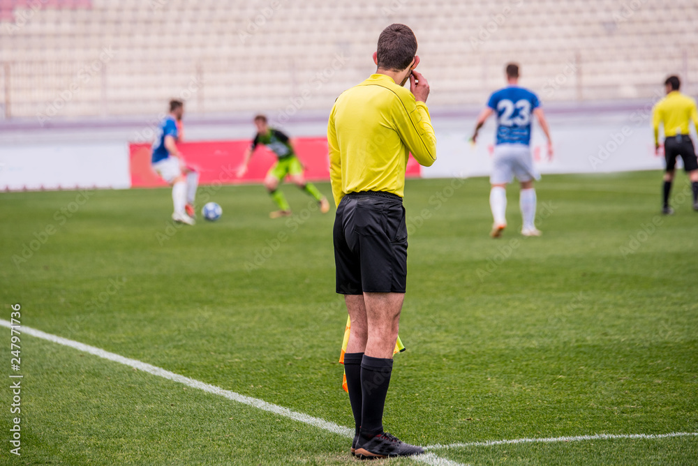 Football referee during soccer match, players in background