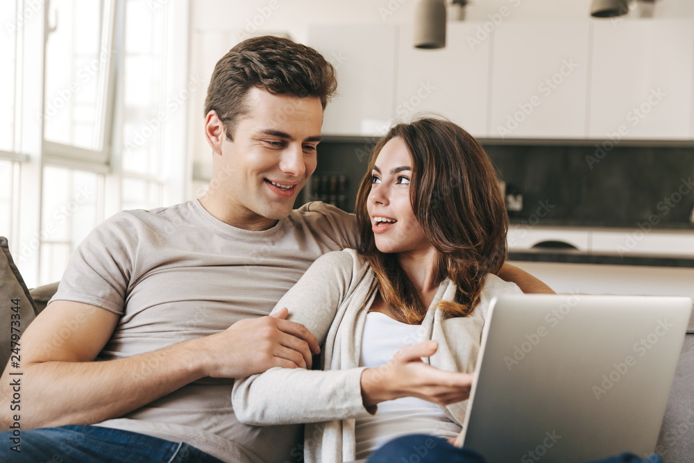 Smiling young couple relaxing on a couch at home Smiling young couple relaxing on a couch at home