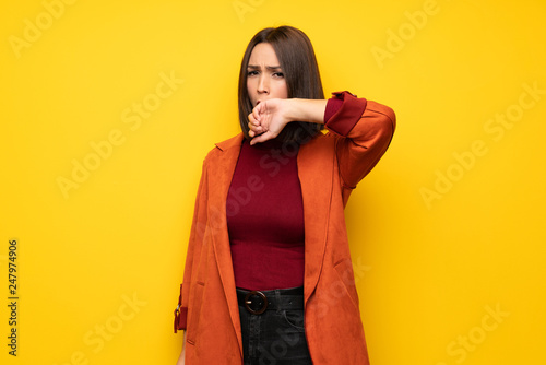 Young woman with coat yawning and covering wide open mouth with hand © luismolinero