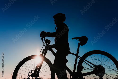 silhouette of a Cyclist Riding the Bike Down Rocky Hill at Sunset. Extreme Sport Concept.