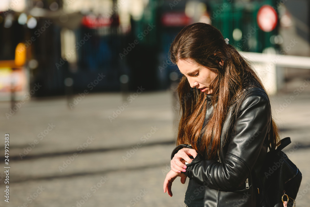 Fototapeta premium Young woman arrives late for an appointment, while waiting in the street.
