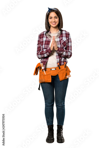 A full-length shot of a Young worker woman keeps palm together. Person asks for something over isolated white background
