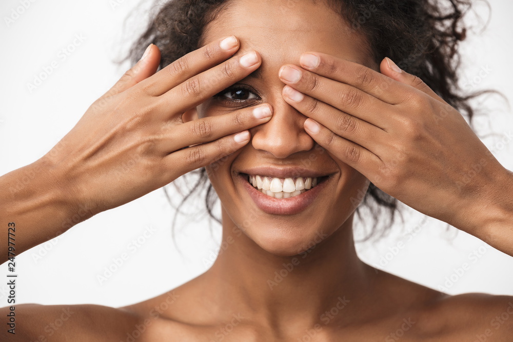 Young african woman posing isolated over white wall background covering eyes with hands.