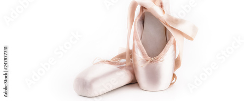 Pointe shoes ballet dance shoes with a bow of ribbons beautifully folded on a white background with a lot of light.