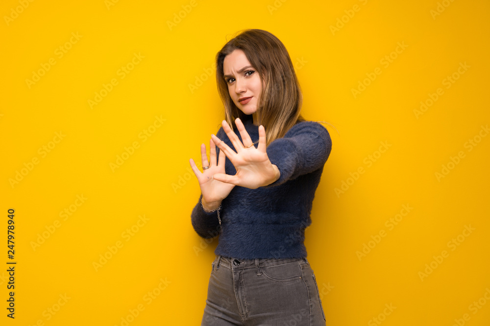 Teenager girl over yellow wall nervous and scared stretching hands to the front Teenager girl over yellow wall nervous and scared stretching hands to the front