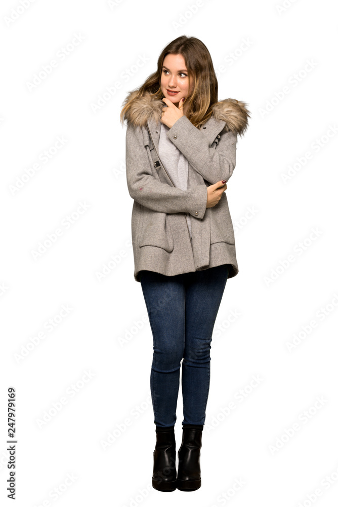 A full-length shot of a Teenager girl with coat looking to the side with the hand on the chin on isolated white background A full-length shot of a Teenager girl with coat looking to the side with the hand on the chin on isolated white background