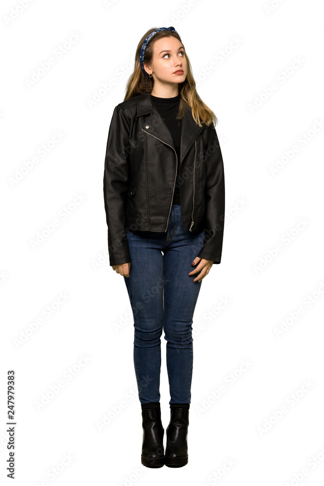 A full-length shot of a Teenager girl with leather jacket looking up with serious face on isolated white background A full-length shot of a Teenager girl with leather jacket looking up with serious face on isolated white background