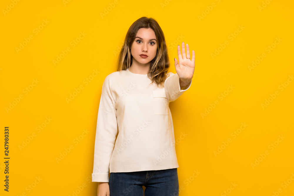 Teenager girl over yellow wall making stop gesture denying a situation that thinks wrong Teenager girl over yellow wall making stop gesture denying a situation that thinks wrong