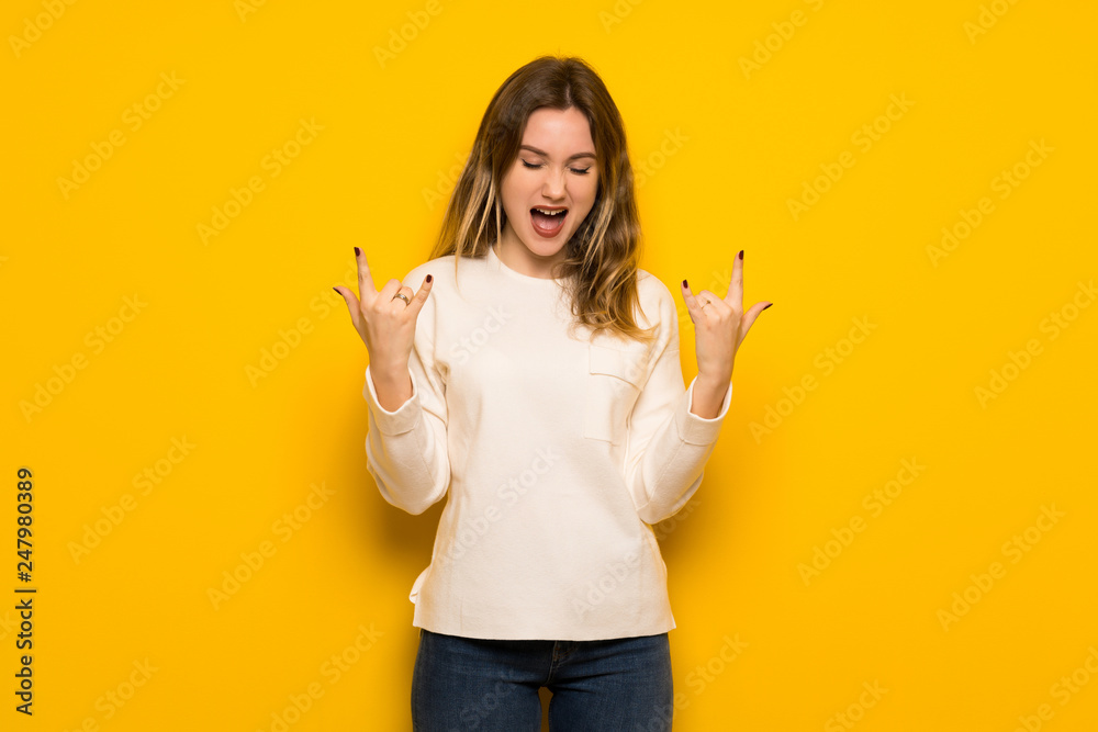 Teenager girl over yellow wall making rock gesture Teenager girl over yellow wall making rock gesture