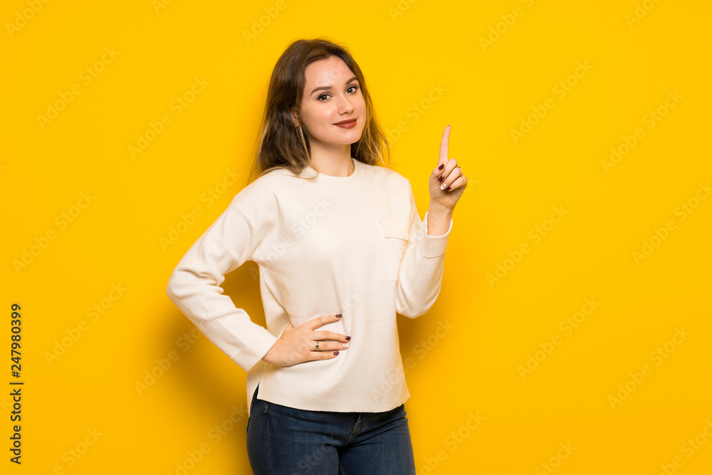 Teenager girl over yellow wall showing and lifting a finger in sign of the best Teenager girl over yellow wall showing and lifting a finger in sign of the best