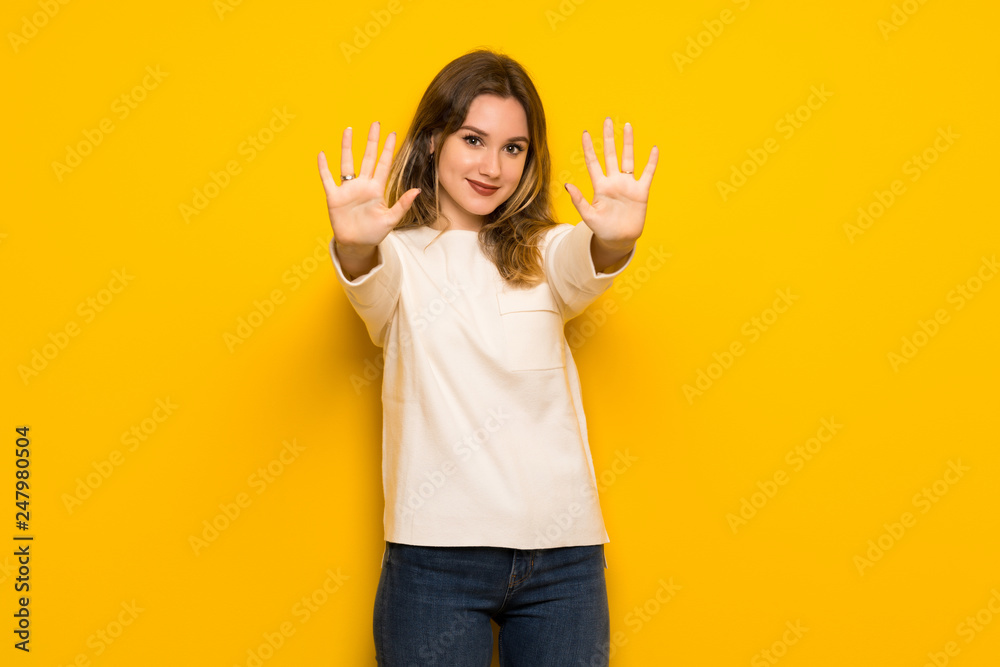 Teenager girl over yellow wall counting ten with fingers Teenager girl over yellow wall counting ten with fingers
