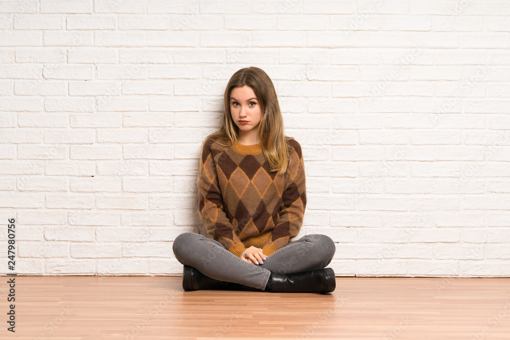 Teenager girl sitting on the floor with sad and depressed expression Teenager girl sitting on the floor with sad and depressed expression