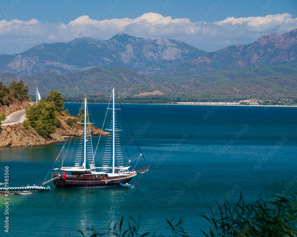 A classic traditional wooden Turkish pleasure yacht anchored in the pantone in the picturesque bay of Fethiye in the Mediterranean Sea against the backdrop of a mountain range in Fethiye,Mugla,Turkey