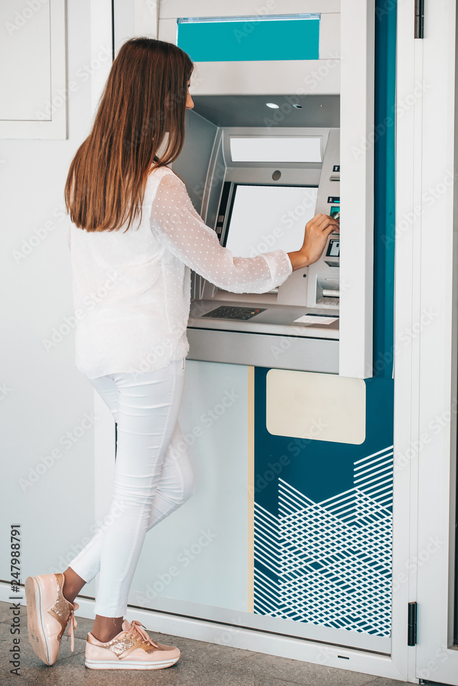Young woman withdrawing money from credit card at ATM Young woman withdrawing money from credit card at ATM