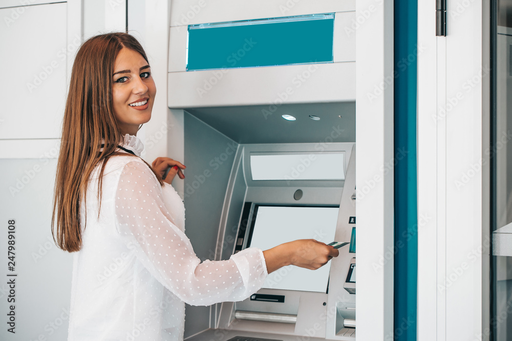 Smiling woman withdrawing money from credit card at ATM Smiling woman withdrawing money from credit card at ATM