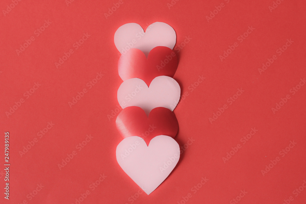 Pink and red hearts creating center placed line, free copy space, selective focus, red background, blurred