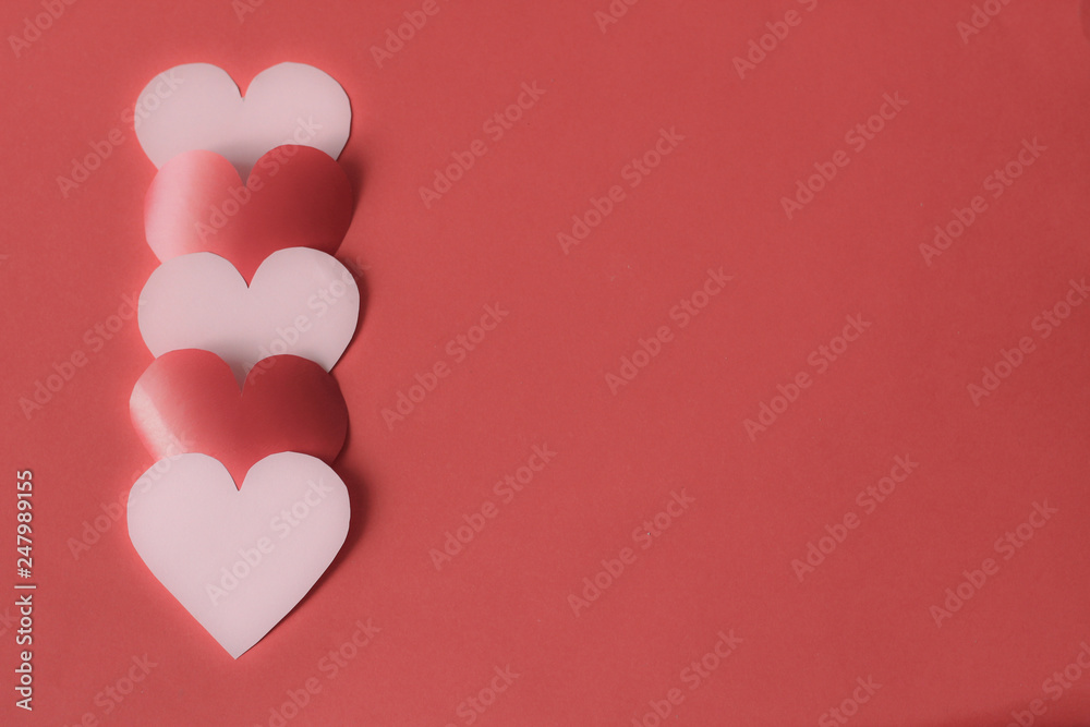 Pink and red hearts creating left placed line, free copy space, selective focus, red background, blurred