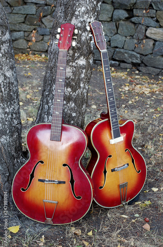 Two acoustic jazz guitars on the stone wall background